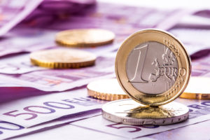 Several 500 euro banknotes and coins are adjacent. Symbolic photo for wealt.Euro coin balancing on stack with background of banknotes.