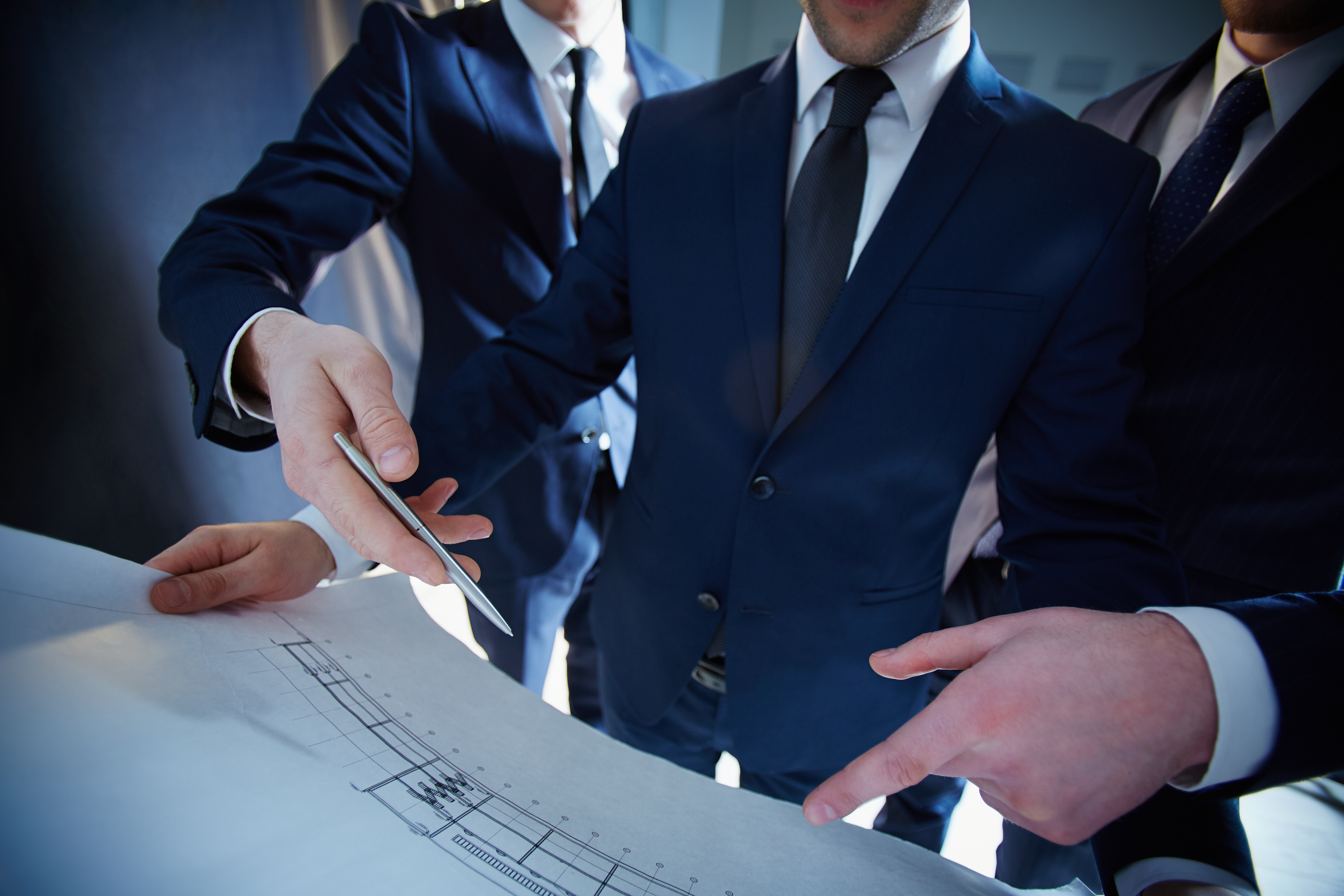 Cropped image of professional engineers working with the construction blue print on the foreground